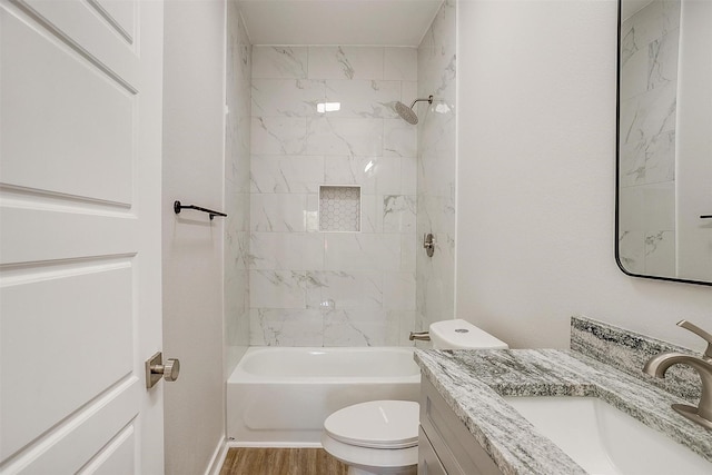 full bathroom featuring hardwood / wood-style flooring, tiled shower / bath, vanity, and toilet