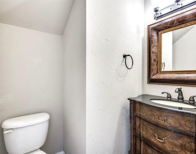 bathroom featuring vanity, toilet, and vaulted ceiling