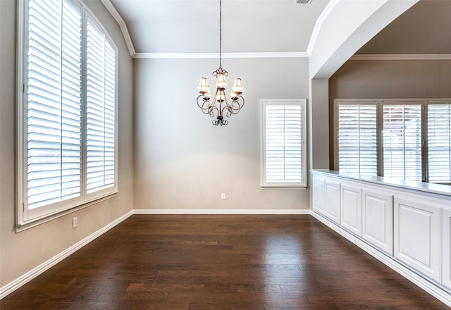 empty room featuring crown molding, dark hardwood / wood-style floors, and an inviting chandelier