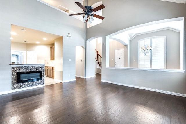 unfurnished living room featuring lofted ceiling, ceiling fan with notable chandelier, a fireplace, and wood-type flooring