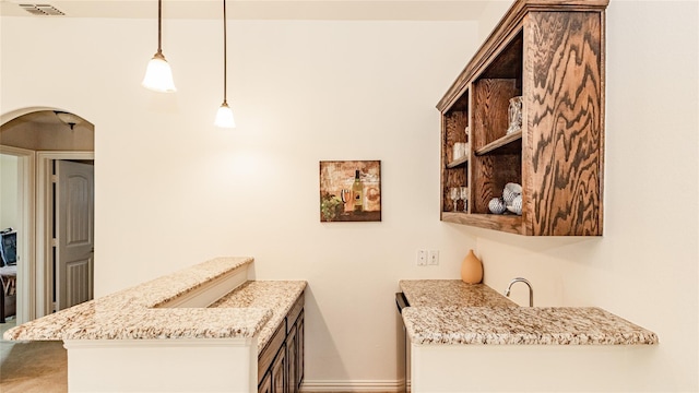 kitchen featuring pendant lighting, light stone countertops, and kitchen peninsula