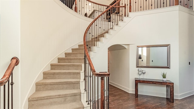 stairway with a towering ceiling and wood-type flooring