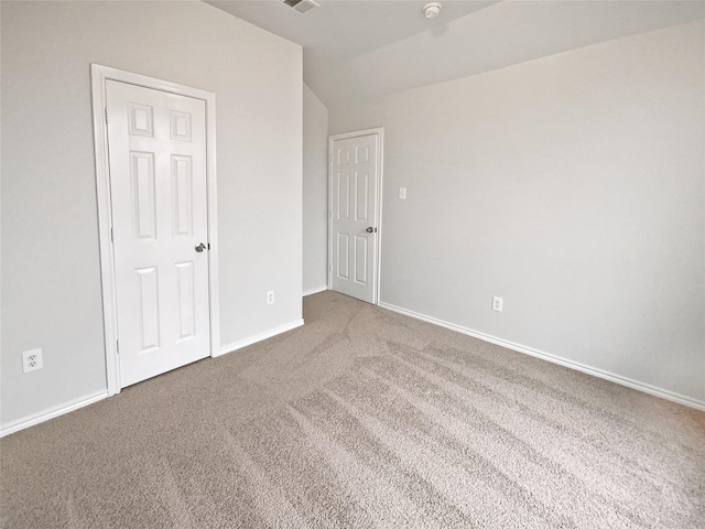 unfurnished bedroom with carpet flooring and vaulted ceiling