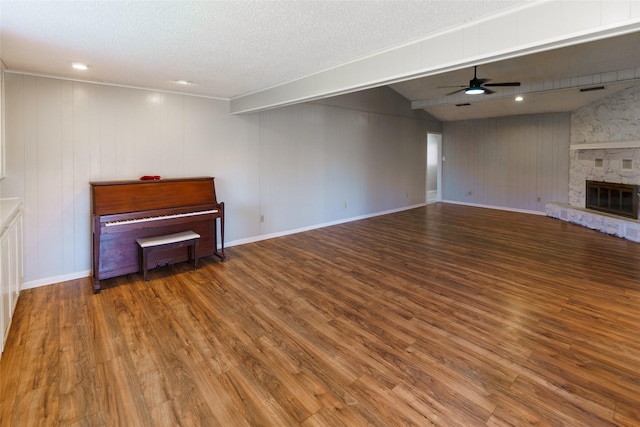 unfurnished living room featuring ceiling fan, a fireplace, hardwood / wood-style floors, and a textured ceiling