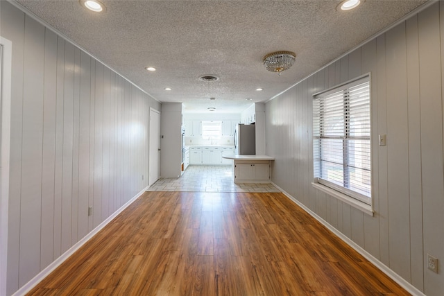 unfurnished room featuring ornamental molding, a textured ceiling, and light wood-type flooring