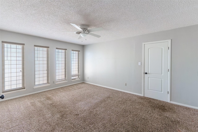 carpeted spare room featuring a textured ceiling, a wealth of natural light, and ceiling fan