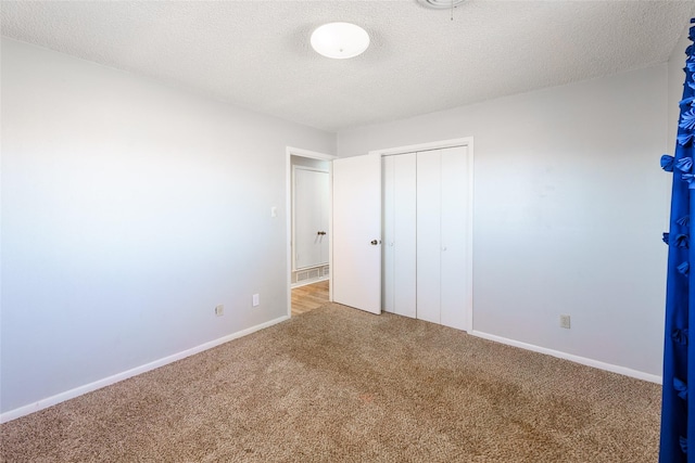 unfurnished bedroom featuring a closet, a textured ceiling, and carpet flooring