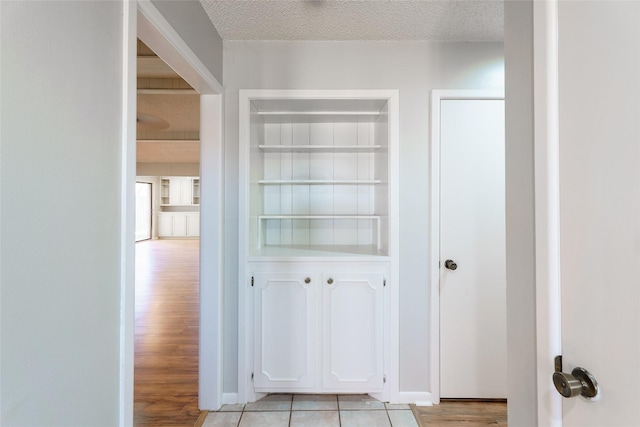 corridor with a textured ceiling and light wood-type flooring