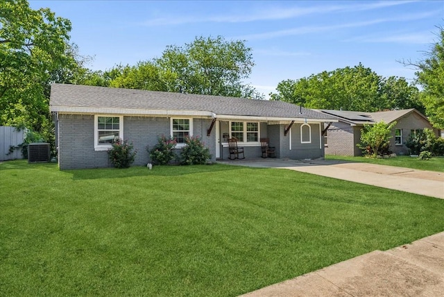 ranch-style house featuring central AC, a front yard, solar panels, and covered porch