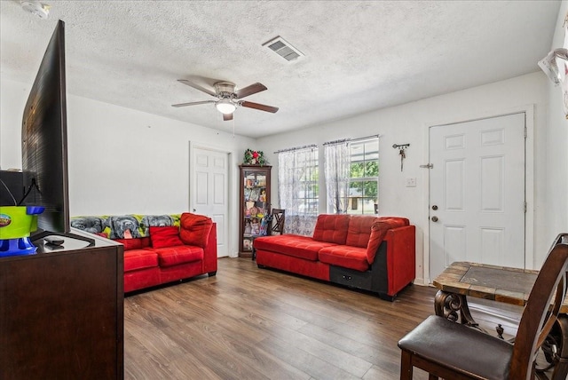 living room featuring ceiling fan, hardwood / wood-style flooring, and a textured ceiling