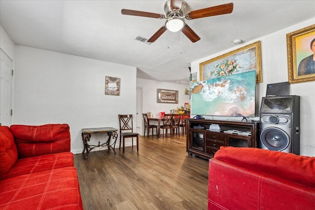 living room featuring ceiling fan, dark hardwood / wood-style flooring, and a textured ceiling