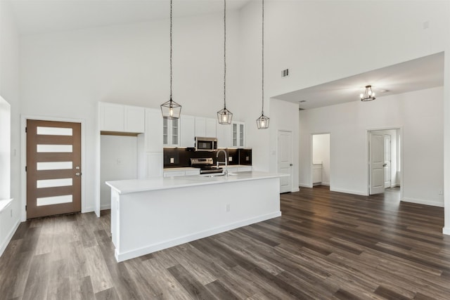 kitchen featuring appliances with stainless steel finishes, a kitchen island with sink, hanging light fixtures, and white cabinets