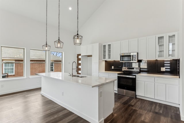 kitchen featuring decorative light fixtures, an island with sink, sink, white cabinets, and stainless steel appliances