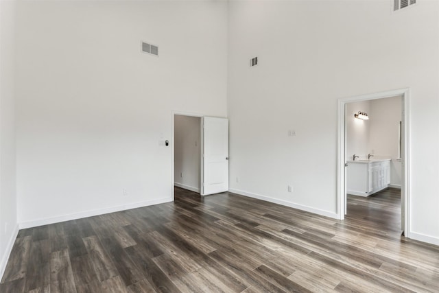 spare room with a towering ceiling and dark hardwood / wood-style flooring