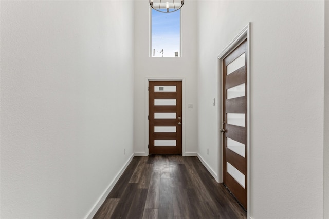 doorway to outside with dark wood-type flooring and a notable chandelier