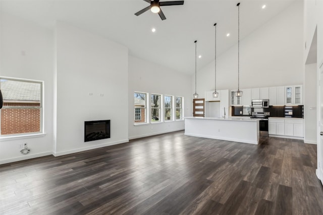 unfurnished living room with sink, high vaulted ceiling, dark hardwood / wood-style floors, and ceiling fan