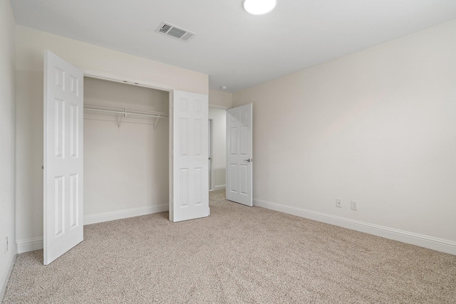 unfurnished bedroom featuring light carpet and a closet