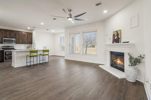 kitchen featuring a breakfast bar, sink, a center island with sink, dark hardwood / wood-style flooring, and stainless steel appliances