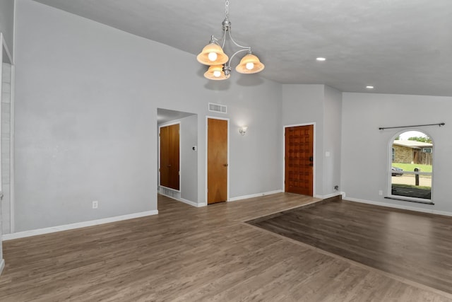 empty room with high vaulted ceiling, an inviting chandelier, and dark hardwood / wood-style flooring