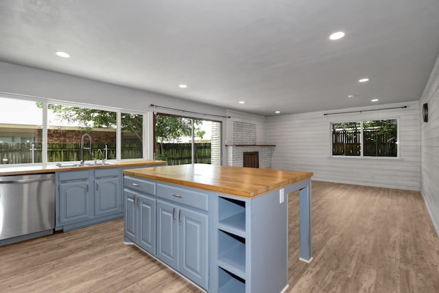 kitchen featuring sink, butcher block counters, stainless steel dishwasher, blue cabinetry, and light hardwood / wood-style flooring