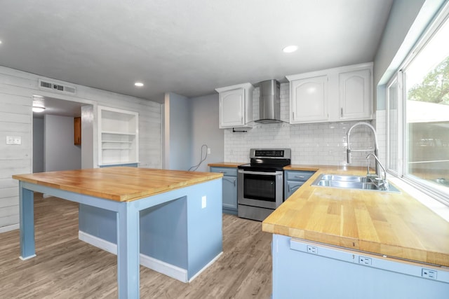 kitchen featuring sink, white cabinetry, stainless steel range with electric stovetop, wood counters, and wall chimney exhaust hood