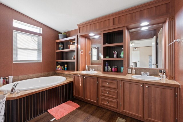 bathroom featuring vanity, vaulted ceiling, wood-type flooring, and a bathtub