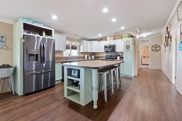 kitchen featuring white cabinetry, a kitchen island, a kitchen breakfast bar, and appliances with stainless steel finishes