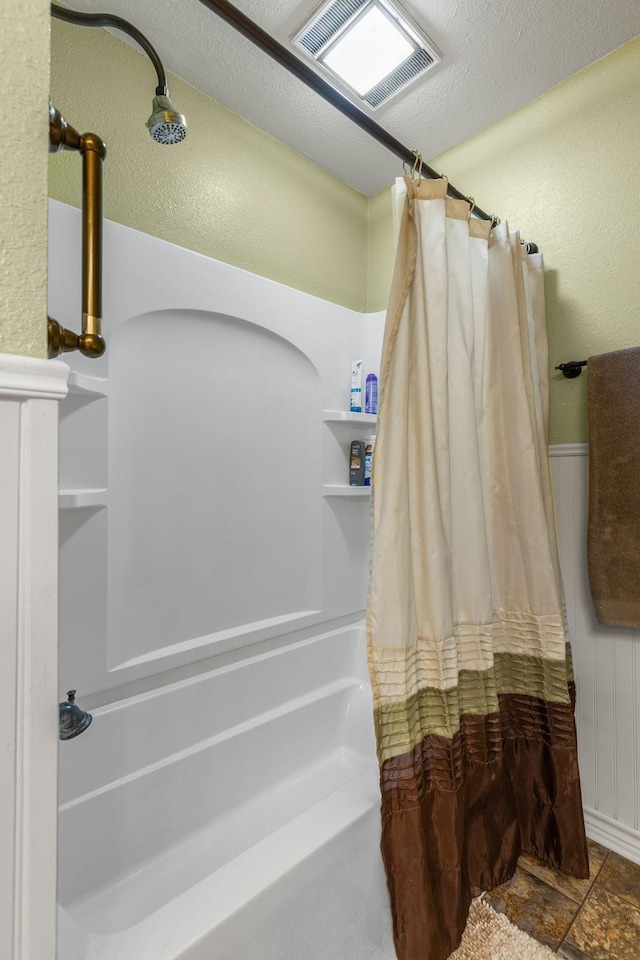 bathroom with shower / bathtub combination with curtain and a textured ceiling