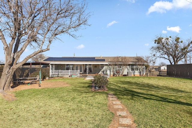 rear view of house featuring a trampoline, a lawn, and solar panels