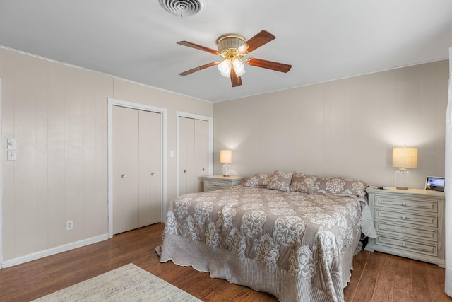 bedroom featuring multiple closets, hardwood / wood-style floors, and ceiling fan