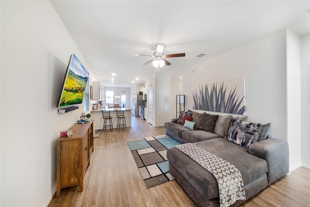 living room with light hardwood / wood-style flooring and ceiling fan