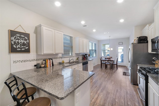 kitchen with white cabinetry, hanging light fixtures, stainless steel appliances, and kitchen peninsula