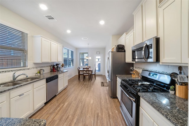 kitchen featuring white cabinetry, stainless steel appliances, sink, and pendant lighting