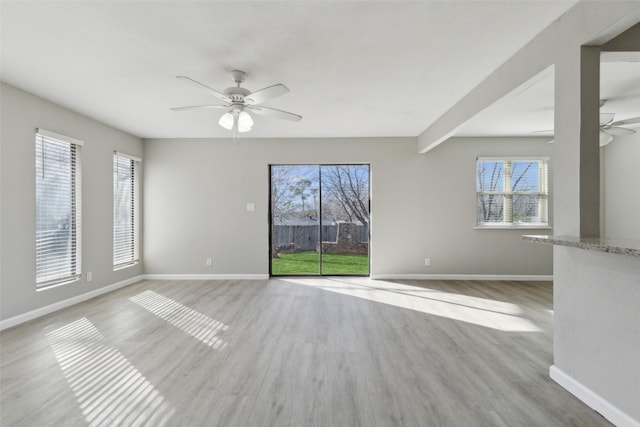 spare room with ceiling fan, light hardwood / wood-style floors, and a wealth of natural light