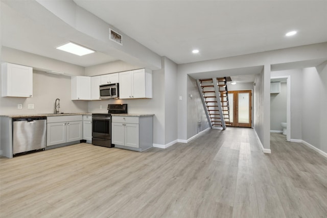 kitchen with white cabinetry, appliances with stainless steel finishes, sink, and light hardwood / wood-style flooring