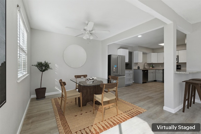 dining room featuring ceiling fan, sink, and light wood-type flooring