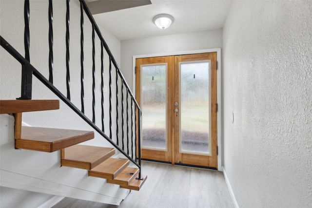 foyer entrance with light hardwood / wood-style floors and french doors