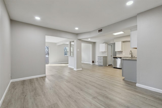 unfurnished living room featuring sink and light hardwood / wood-style floors