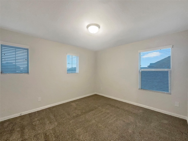 spare room with dark carpet