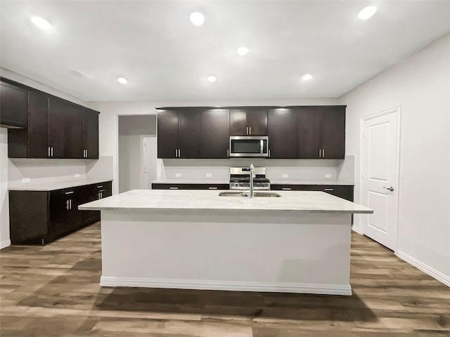 kitchen with dark brown cabinetry, sink, a center island with sink, and appliances with stainless steel finishes