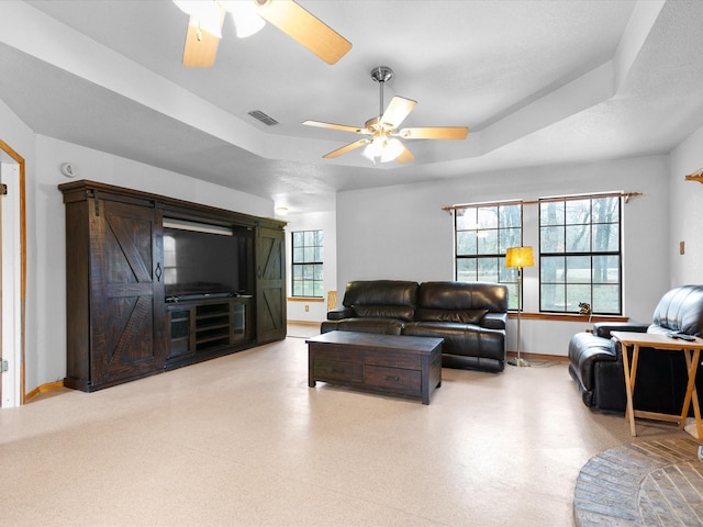 living room with ceiling fan and a tray ceiling