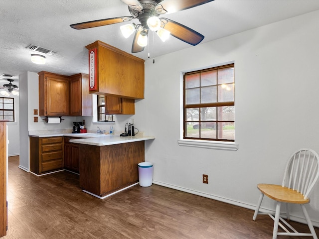 kitchen featuring a breakfast bar area, a textured ceiling, dark hardwood / wood-style flooring, kitchen peninsula, and ceiling fan