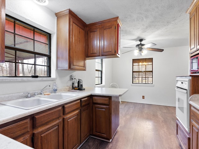 kitchen featuring dark wood-type flooring, sink, a textured ceiling, kitchen peninsula, and oven