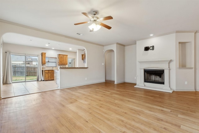 unfurnished living room featuring ornamental molding, ceiling fan, and light wood-type flooring