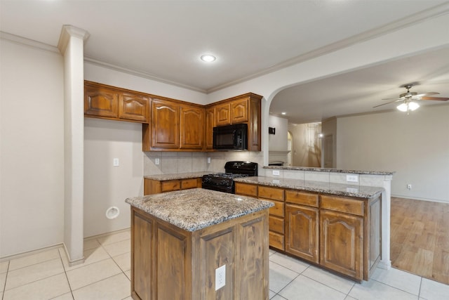 kitchen featuring tasteful backsplash, light tile patterned flooring, a kitchen island, and black appliances