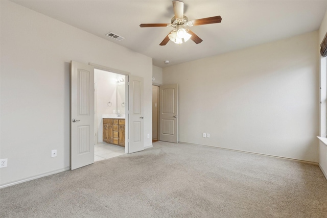 unfurnished bedroom with ceiling fan, light carpet, and ensuite bath