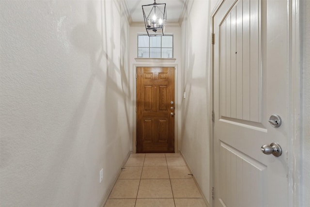 entryway featuring ornamental molding, light tile patterned floors, and a chandelier