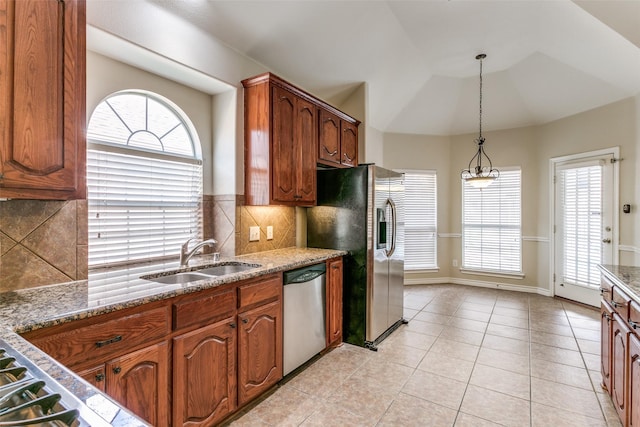 kitchen featuring light tile patterned flooring, vaulted ceiling, decorative light fixtures, sink, and stainless steel appliances