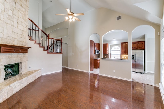 unfurnished living room featuring a fireplace, dark wood-type flooring, high vaulted ceiling, and ceiling fan