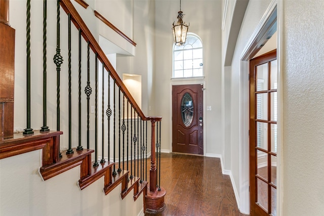 entrance foyer featuring a towering ceiling, dark hardwood / wood-style floors, and a notable chandelier